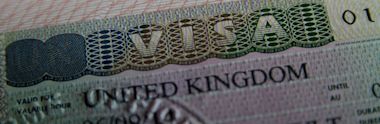 Close-up of a visa document with VISA prominently displayed at the top. The text United Kingdom is visible below, featuring varying fonts and security patterns.